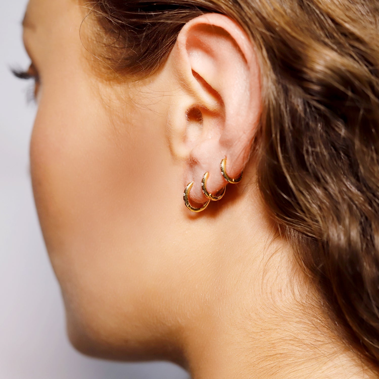 Delicate sterling silver huggie hoop earrings by AJJ, featuring minimalist and lightweight design with a subtle shine.