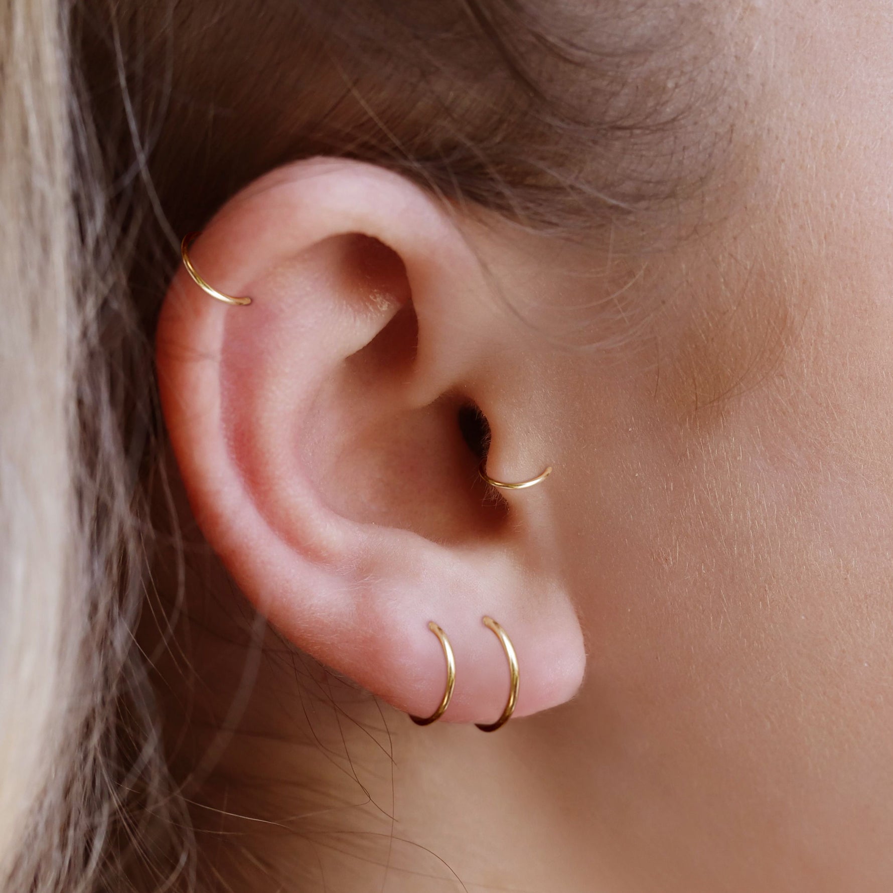 AJJ Tiny Huggie Hoop Earrings featuring plain, dainty helix design, close-up of small silver hoop earrings on a white background.