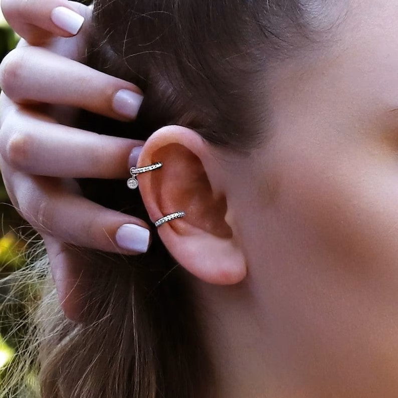 AJJ gold and silver huggie hoop earrings featuring conch, cartilage, tragus, and helix styles with pave ring details.
