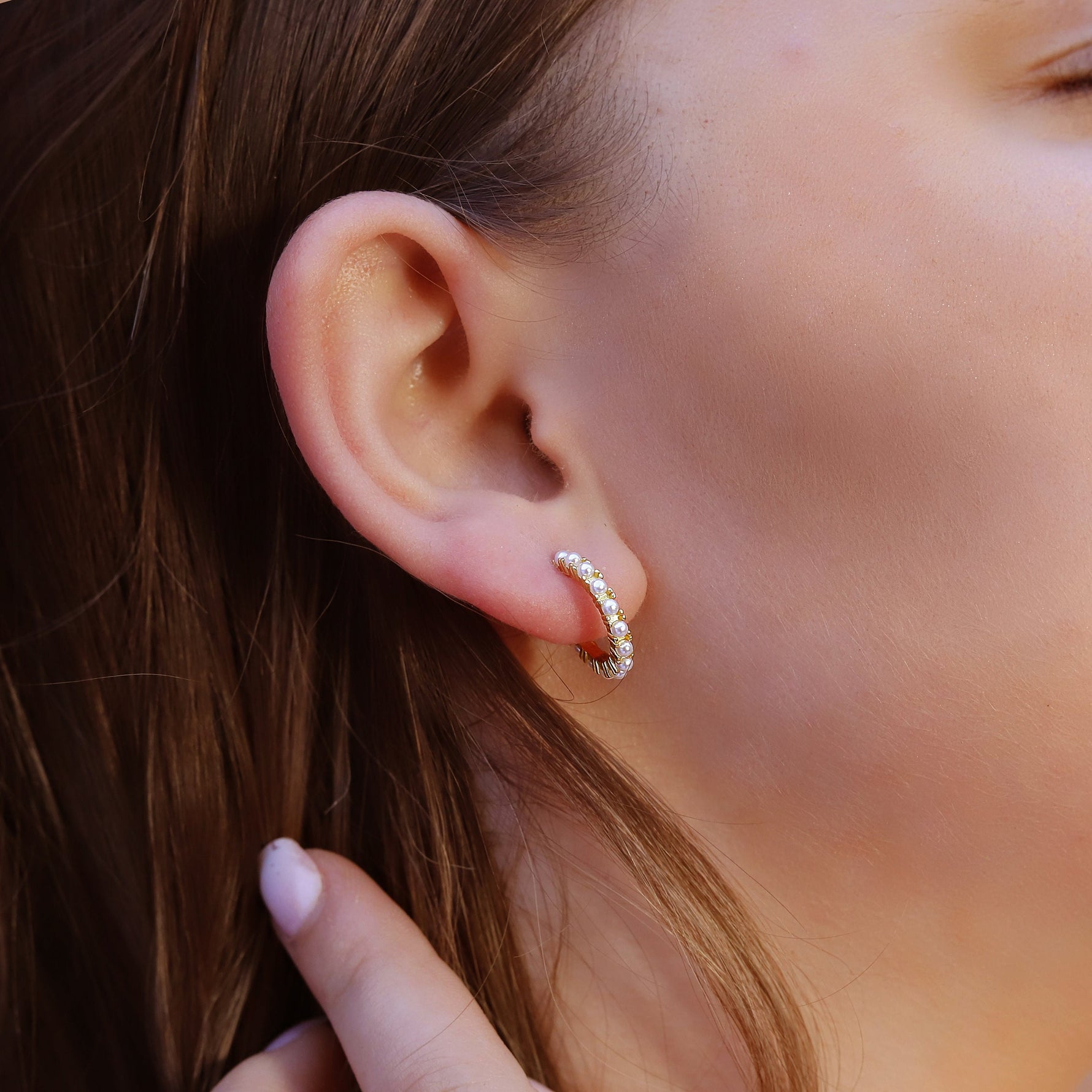 Small silver huggie hoop earrings with pearl accents from AJJ, featuring a minimalist and dainty design.