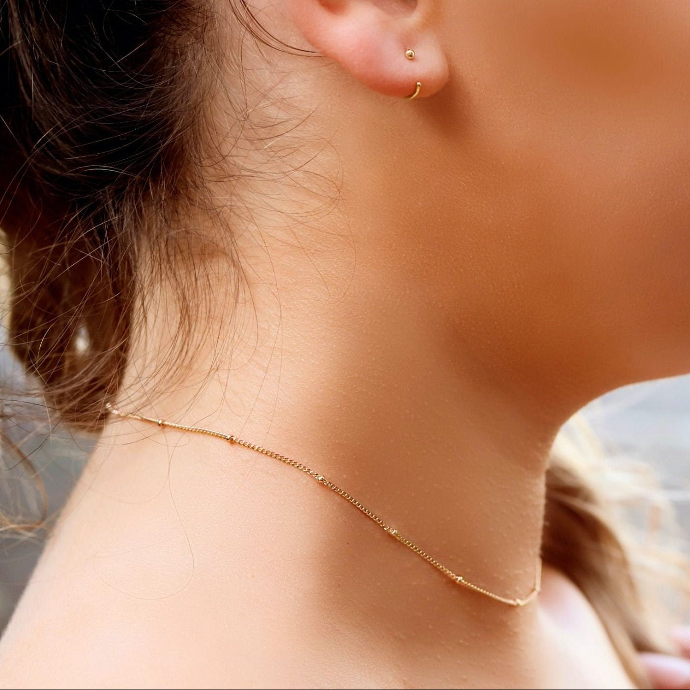 AJJ Niamh gold delicate choker necklace with satellite chain, featuring a fine, elegant design on a model's neck.