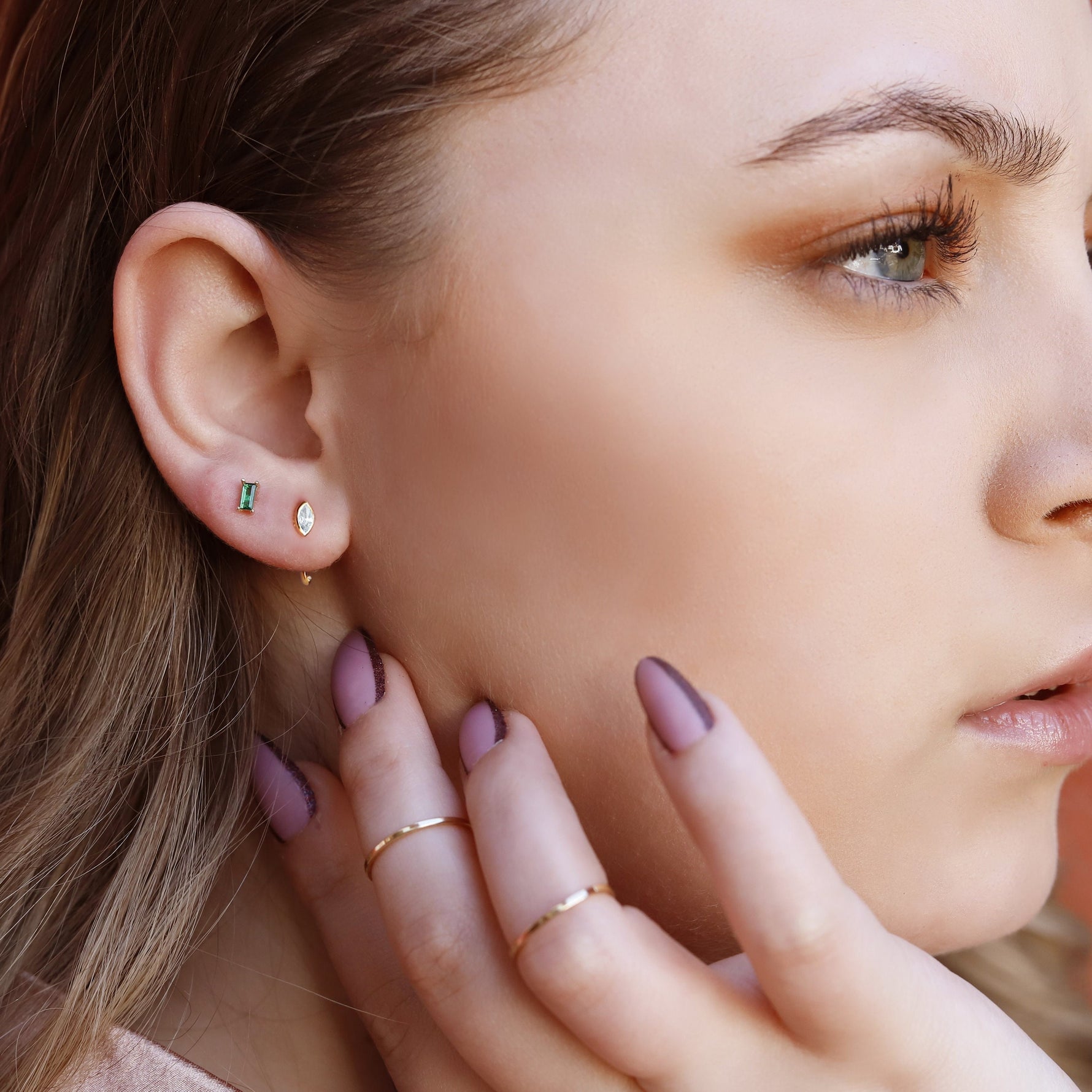 Sterling silver huggie hoop earrings by AJJ, delicate open minimalist geometric silver hoops on a plain background.