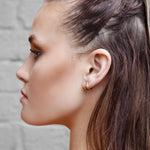 Sterling silver huggie hoop earrings by AJJ, delicate open minimalist geometric silver hoops on a white background.