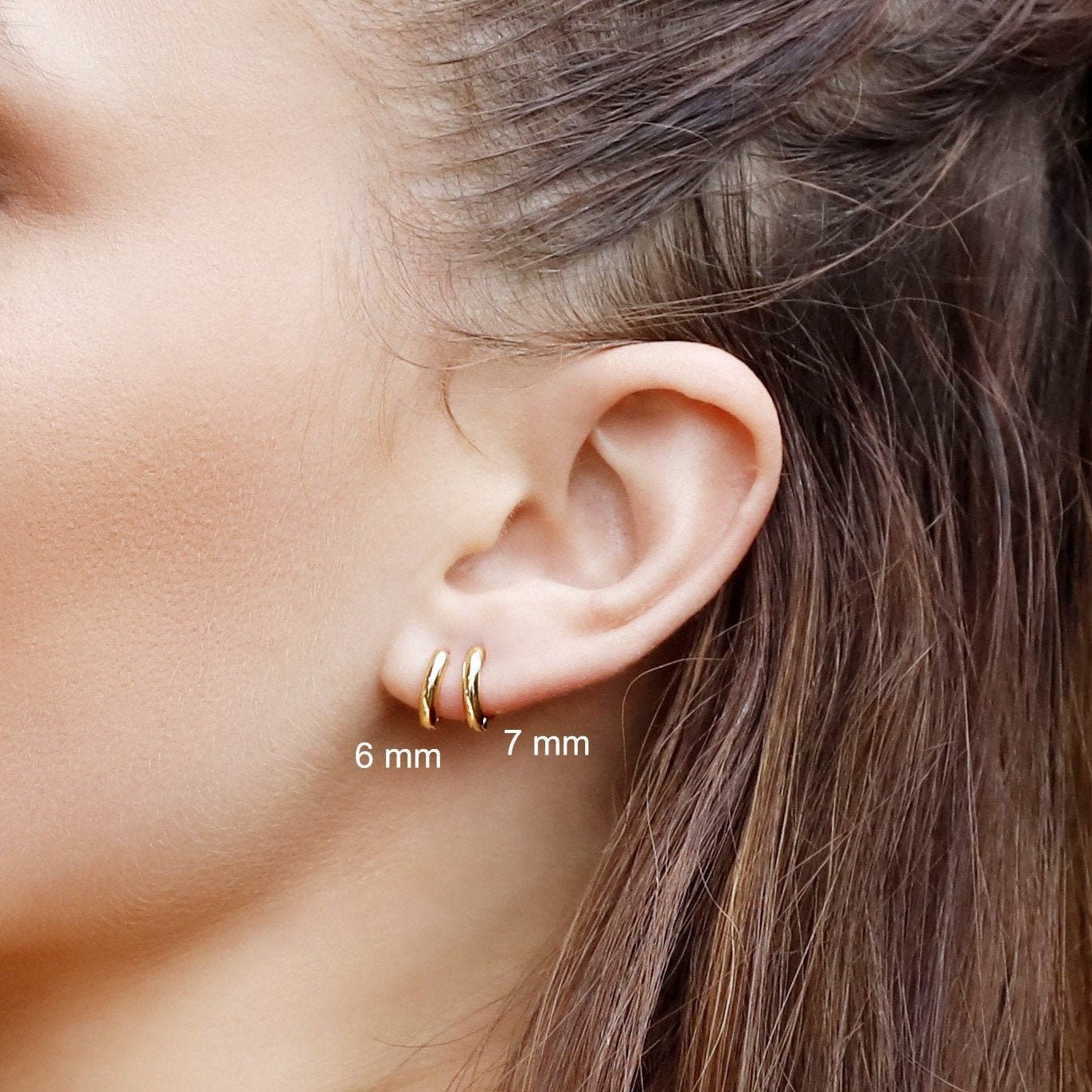 Sterling silver huggie hoop earrings by AJJ with delicate open geometric design, minimalist style, and simple silver finish.