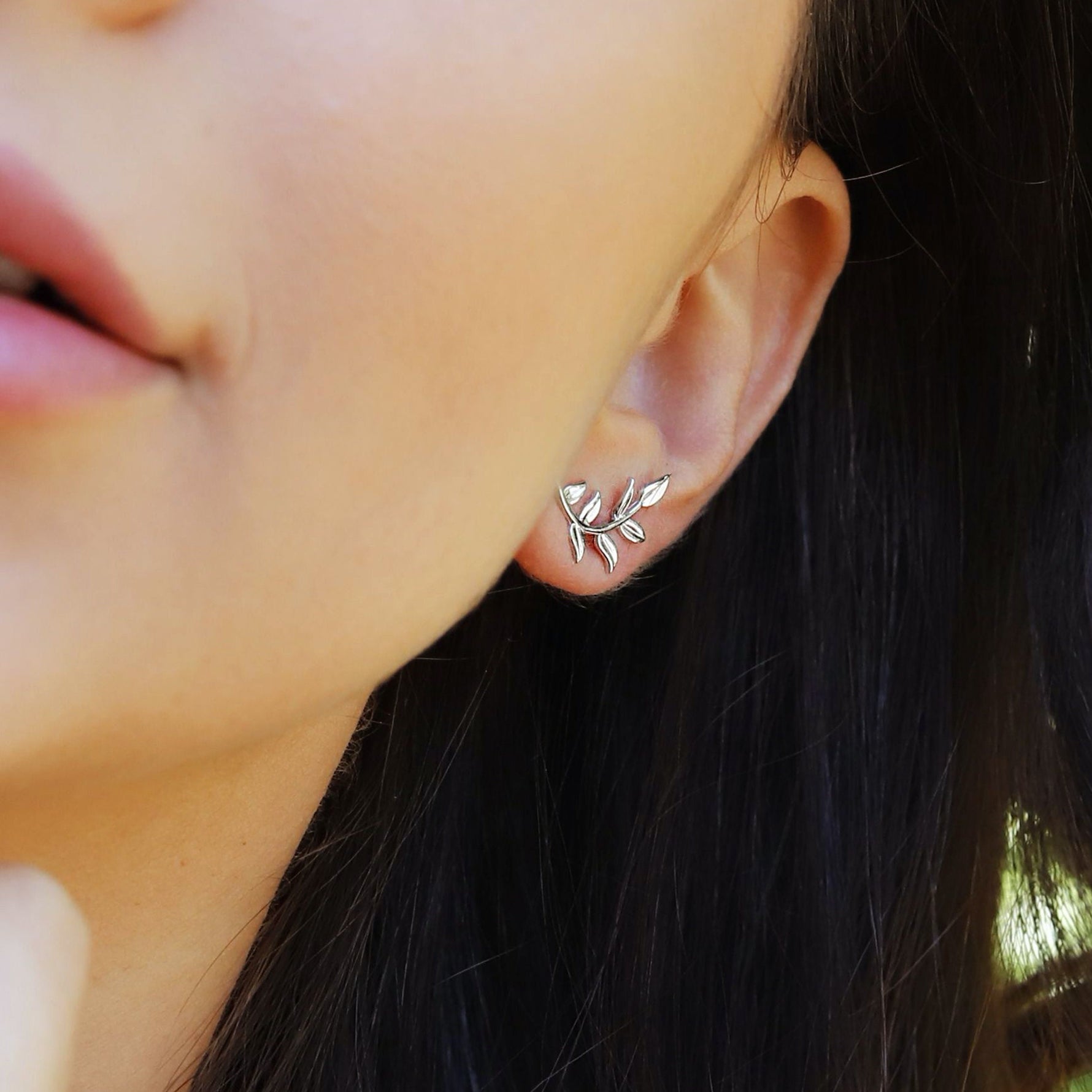 Sterling silver tiny leaves stud earrings with a modern design featuring skinny olive leaves and sparkling accents.
