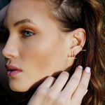 Sterling silver huggie hoop earrings by AJJ, minimalist open hoop design, close-up view showing sleek, polished jewelry.