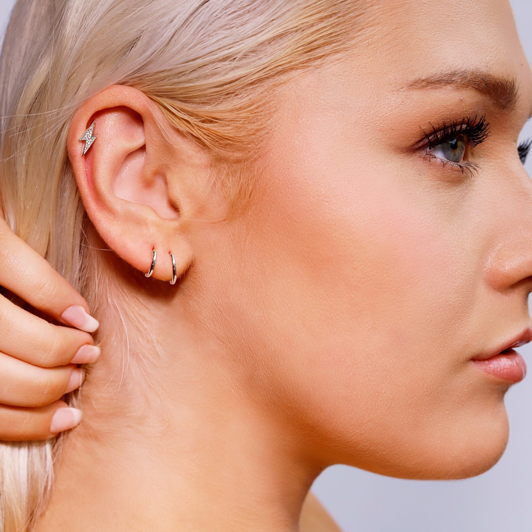 Sterling silver AJJ minimalist open huggie hoop earrings, small and sleek, displayed on a white background.