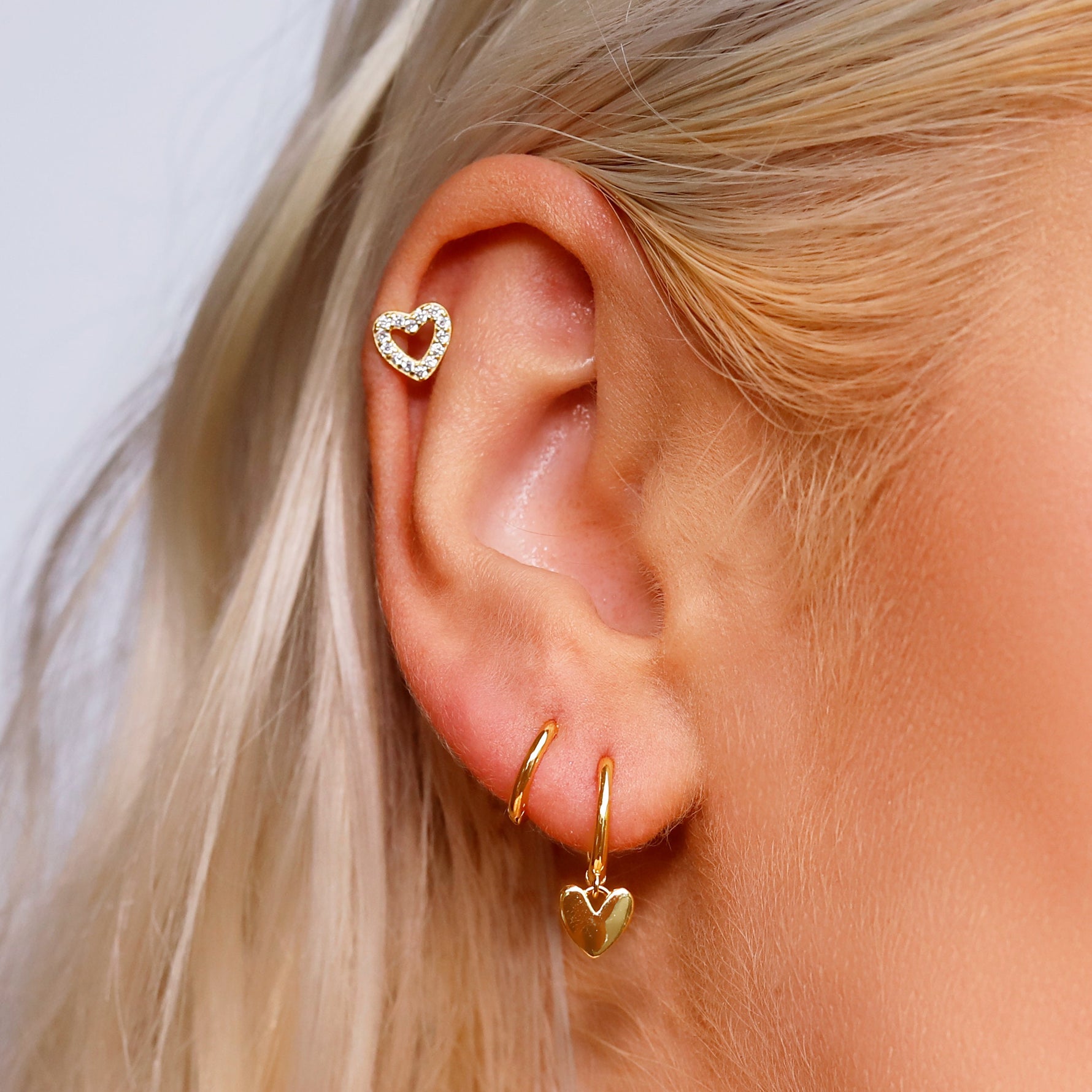 AJJ silver minimalist heart huggie hoops, small dainty silver hoop earrings with tiny heart charms, styled as helix earrings.