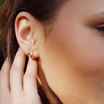 Sterling silver huggie hoop earrings by AJJ featuring minimalist open hoop design, displayed on a white background.