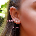 Sterling silver AJJ minimalist open huggie hoop earrings hanging on ear with a sleek, modern design.